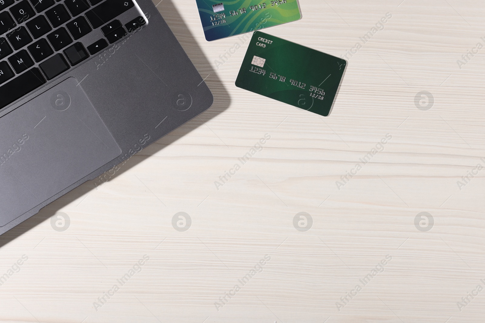 Photo of Online payment. Credit cards and laptop on light wooden table, flat lay. Space for text