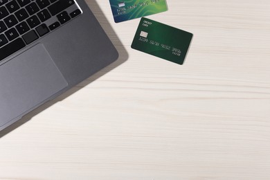 Photo of Online payment. Credit cards and laptop on light wooden table, flat lay. Space for text