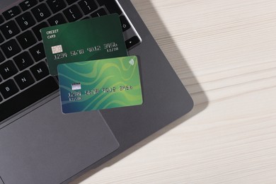 Photo of Online payment. Credit cards and laptop on light wooden table, top view. Space for text