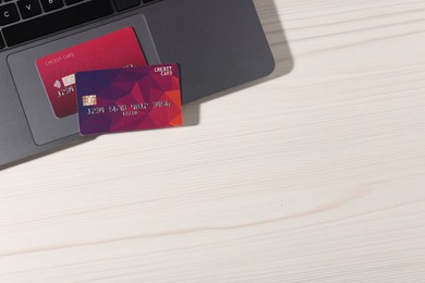 Photo of Online payment. Credit cards and laptop on light wooden table, top view. Space for text