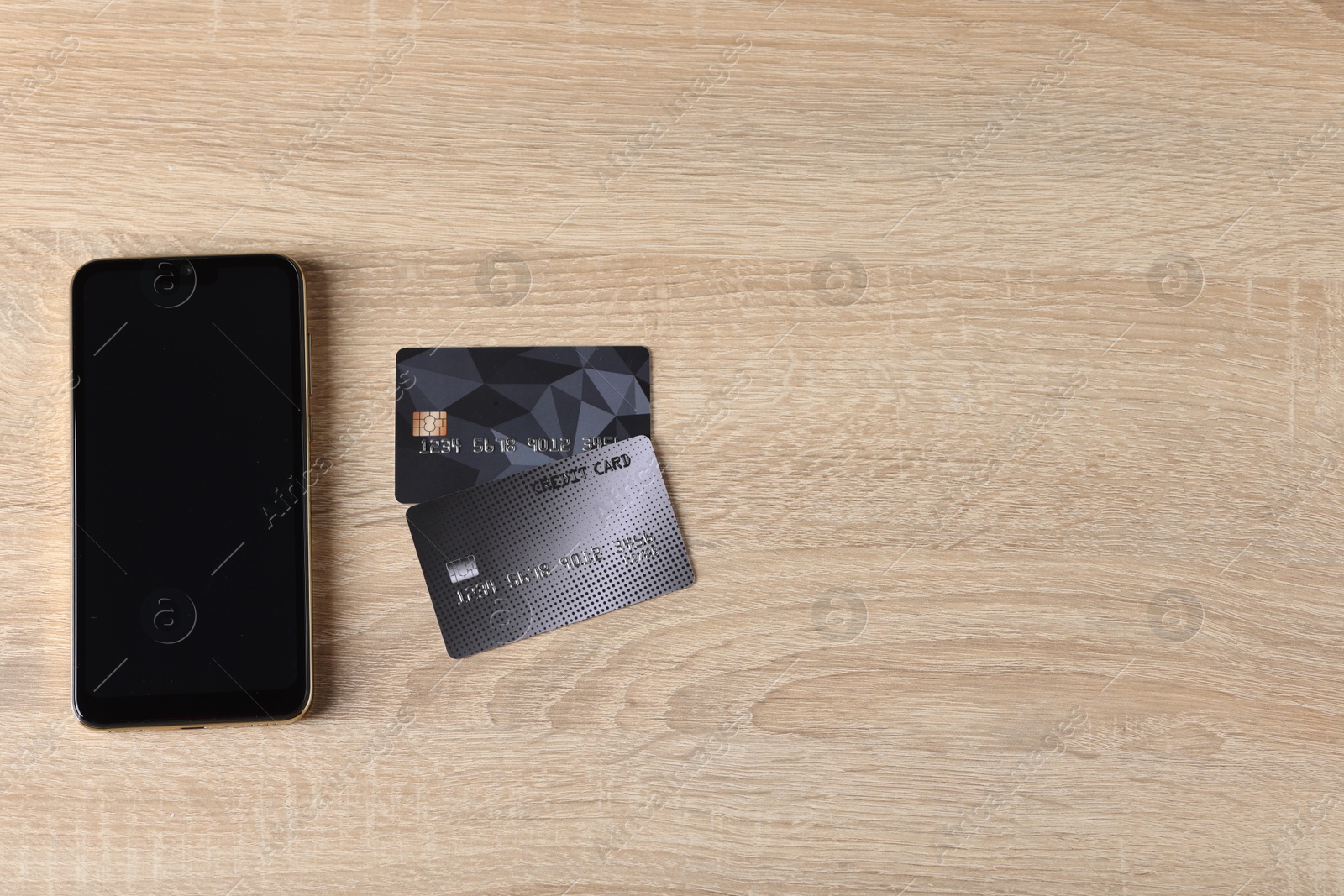 Photo of Online payment. Credit cards and smartphone on wooden table, flat lay. Space for text