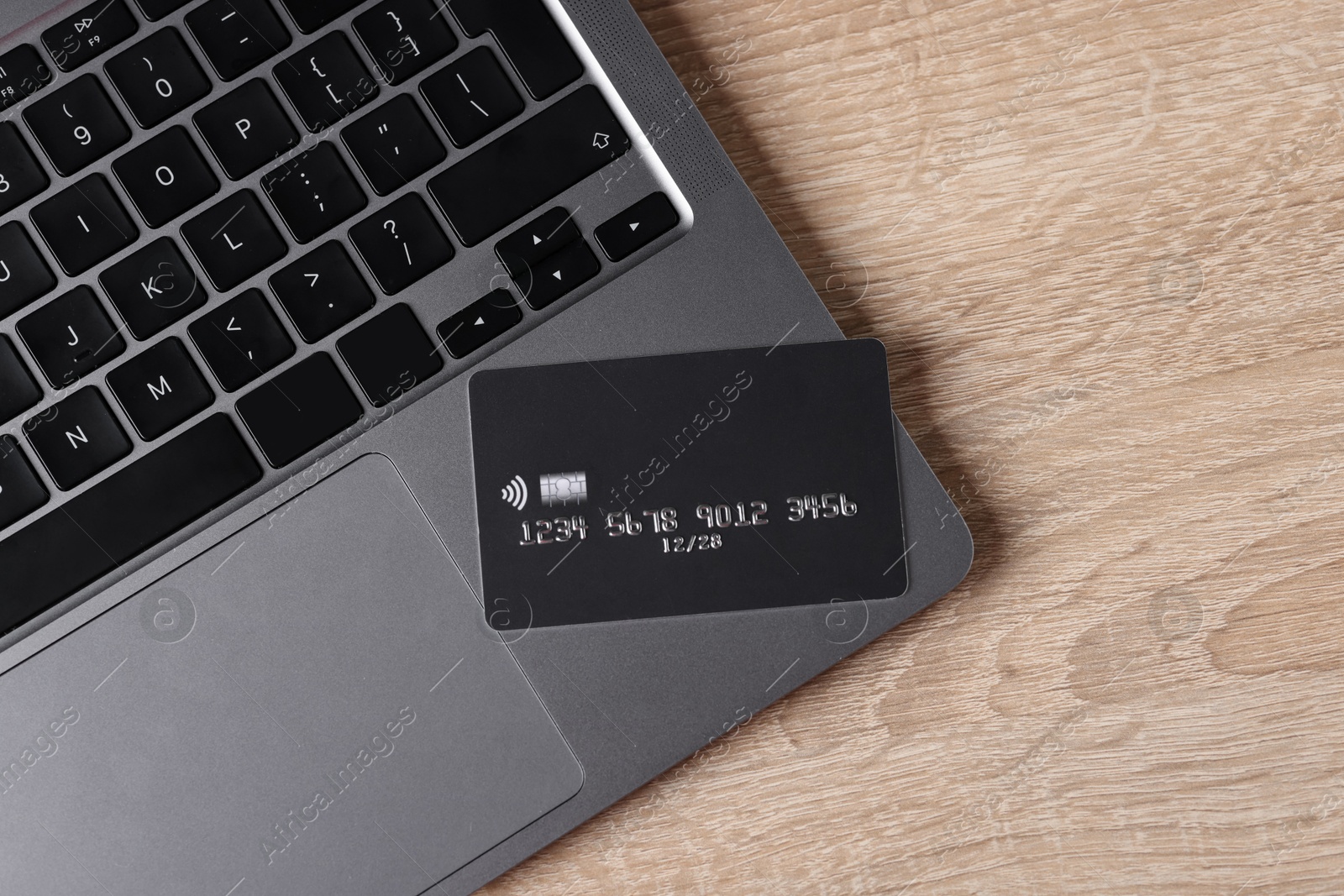 Photo of Online payment. Credit card and laptop on wooden table, top view. Space for text