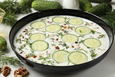 Photo of Fresh tasty cucumber soup and ingredients on white table, closeup