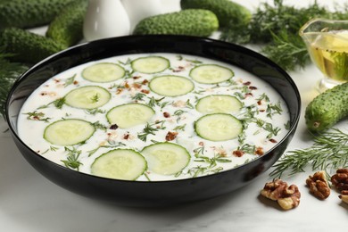 Photo of Fresh tasty cucumber soup and ingredients on white table, closeup