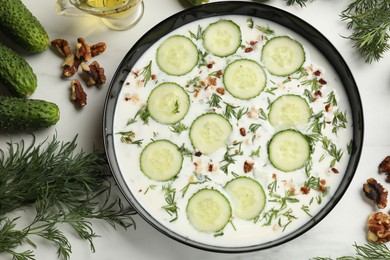 Photo of Fresh tasty cucumber soup and ingredients on white table, flat lay