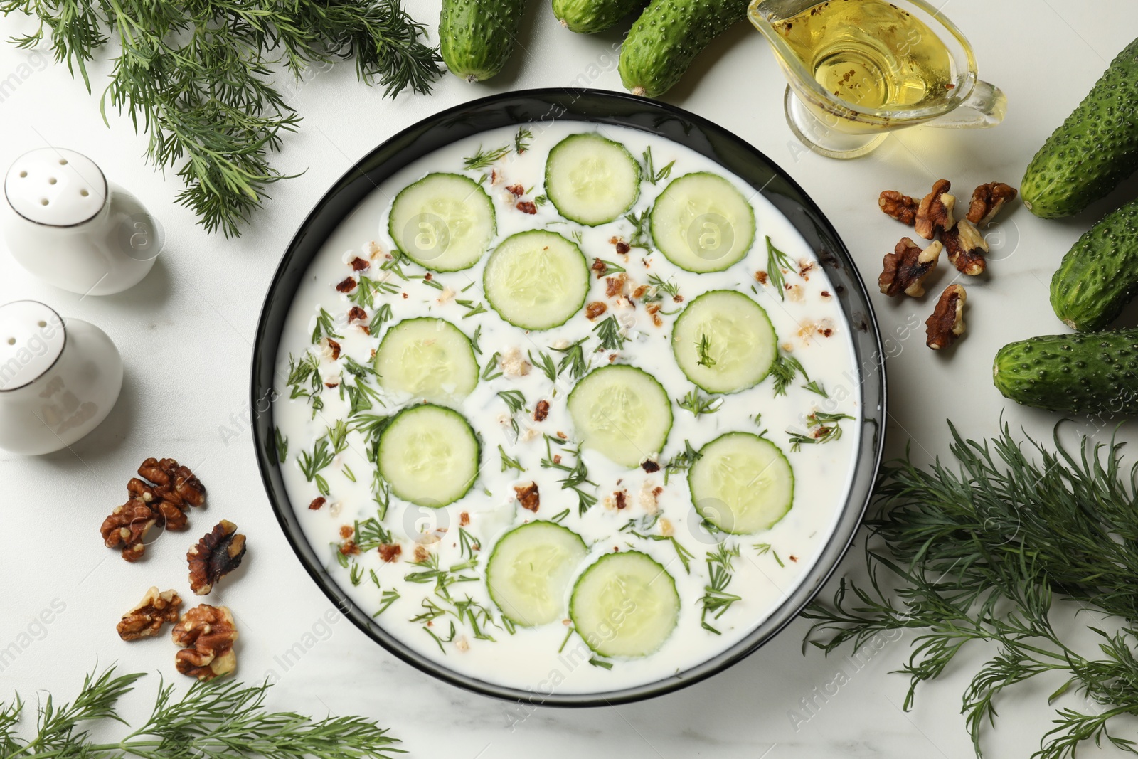 Fresh tasty cucumber soup and ingredients on white table, flat lay Photo of Fresh tasty cucumber soup and ingredients on white table, flat lay