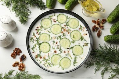 Photo of Fresh tasty cucumber soup and ingredients on white table, flat lay