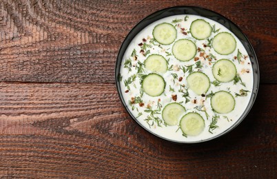 Photo of Fresh tasty cucumber soup on wooden table, top view