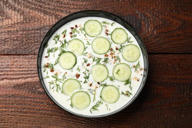 Photo of Fresh tasty cucumber soup on wooden table, top view