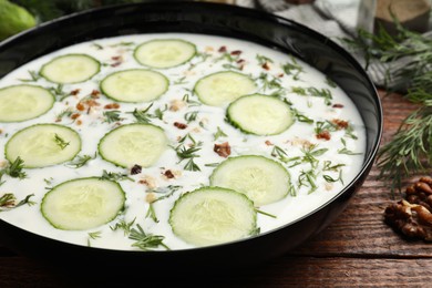 Photo of Fresh tasty cucumber soup and ingredients on wooden table, closeup