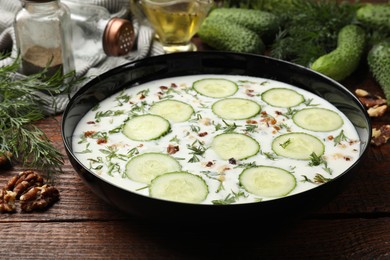 Photo of Fresh tasty cucumber soup and ingredients on wooden table, closeup