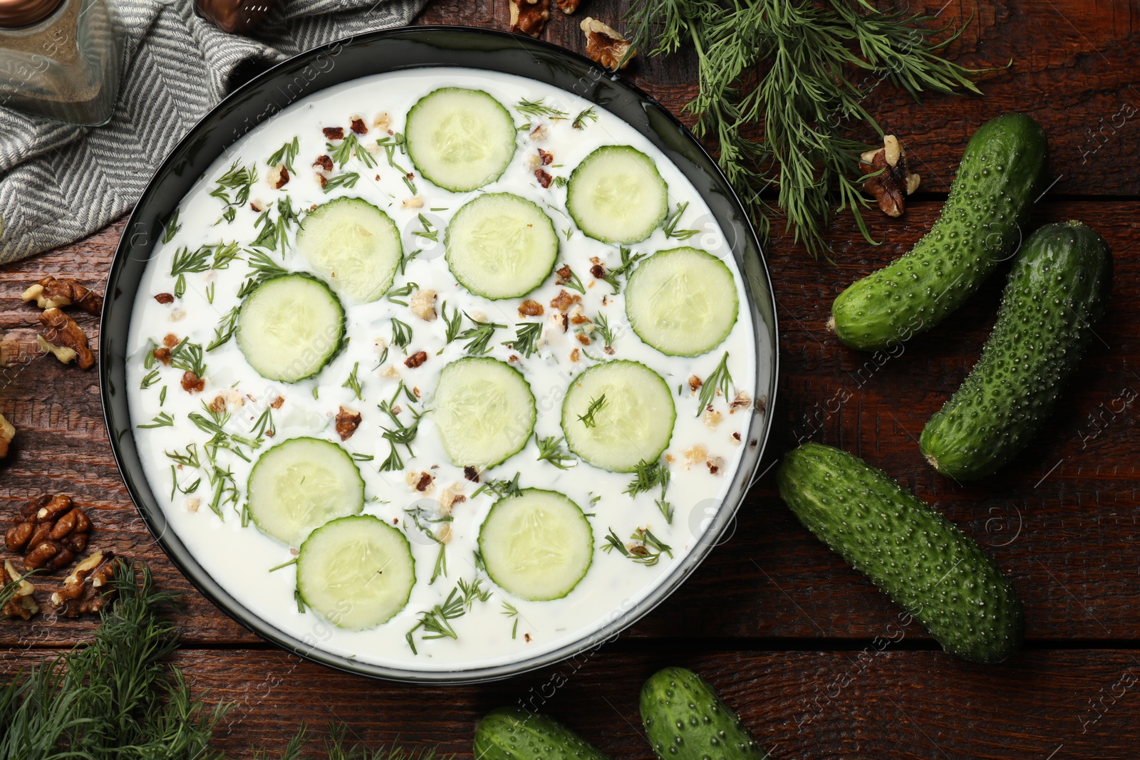 Fresh tasty cucumber soup and ingredients on wooden table, flat lay Photo of Fresh tasty cucumber soup and ingredients on wooden table, flat lay