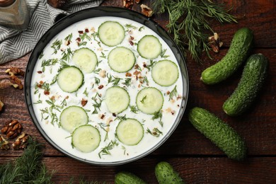 Photo of Fresh tasty cucumber soup and ingredients on wooden table, flat lay