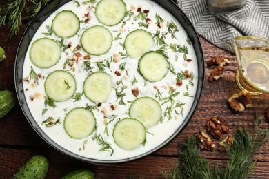 Photo of Fresh tasty cucumber soup and ingredients on wooden table, flat lay
