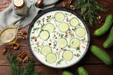 Photo of Fresh tasty cucumber soup and ingredients on wooden table, flat lay