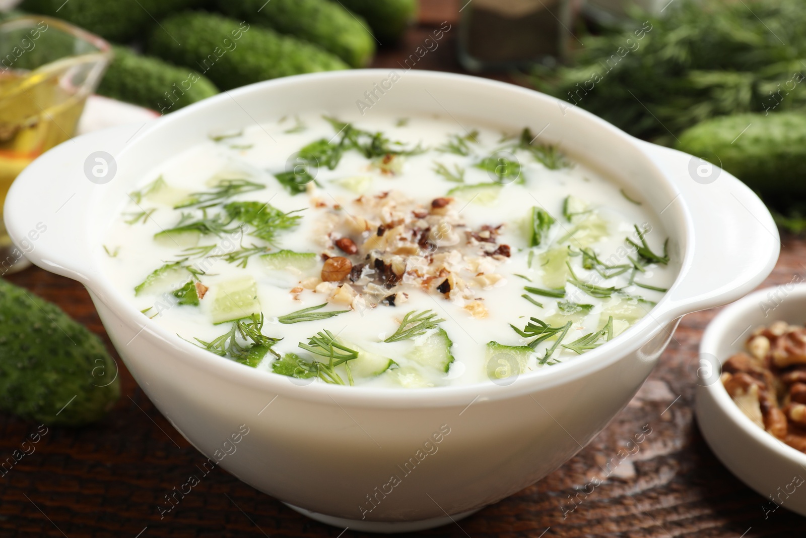 Fresh tasty cucumber soup and ingredients on wooden table, closeup Photo of Fresh tasty cucumber soup and ingredients on wooden table, closeup