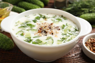 Photo of Fresh tasty cucumber soup and ingredients on wooden table, closeup