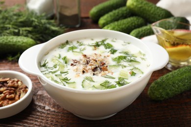 Photo of Fresh tasty cucumber soup and ingredients on wooden table, closeup