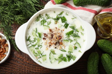 Photo of Fresh tasty cucumber soup and ingredients on wooden table, flat lay