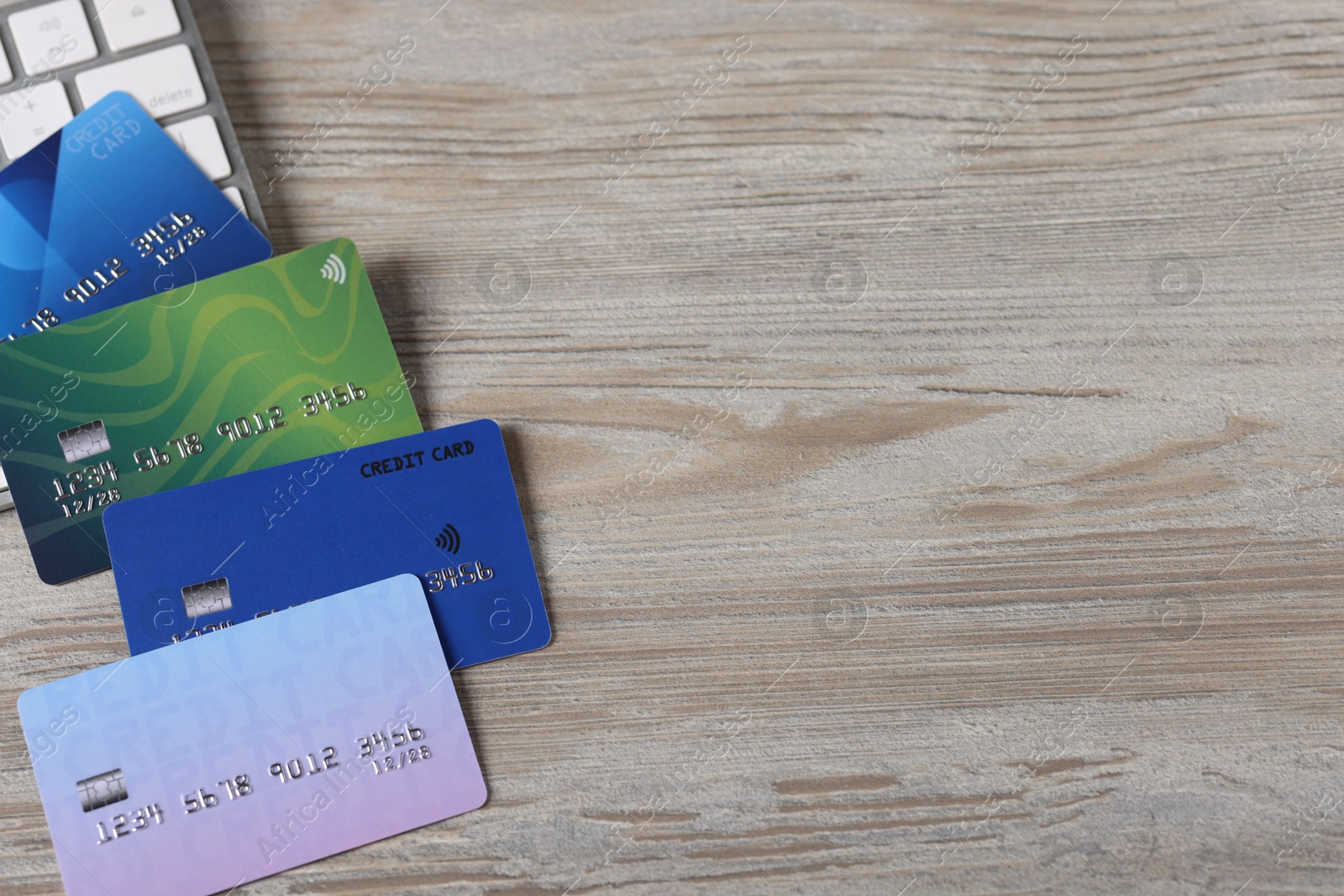 Photo of Online payment. Credit cards and computer keyboard on grey wooden table, flat lay. Space for text