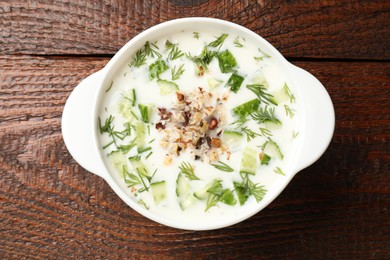 Photo of Fresh tasty cucumber soup on wooden table, top view