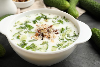 Photo of Fresh tasty cucumber soup and ingredients on black table, closeup