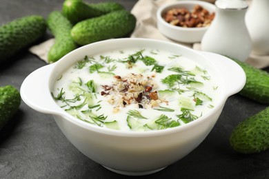 Photo of Fresh tasty cucumber soup and ingredients on black table, closeup