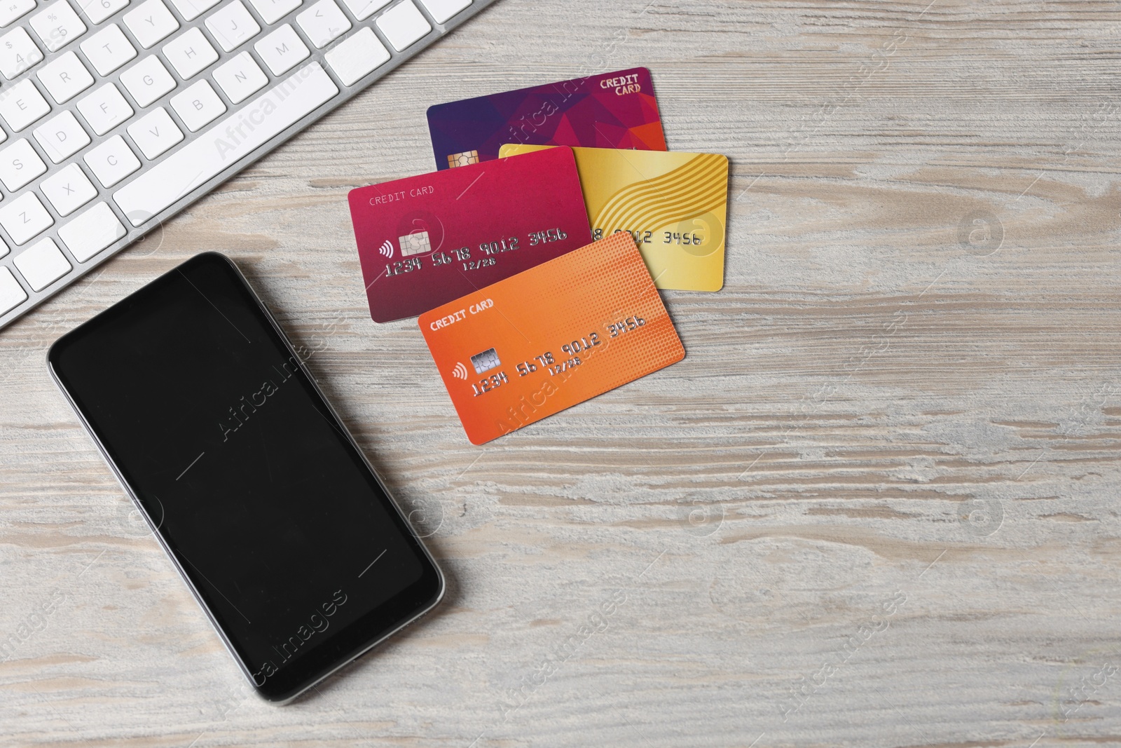 Photo of Online payment. Credit cards, smartphone and computer keyboard on grey wooden table, flat lay. Space for text