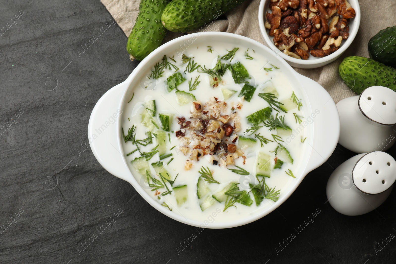 Fresh tasty cucumber soup and ingredients on black table, flat lay Photo of Fresh tasty cucumber soup and ingredients on black table, flat lay