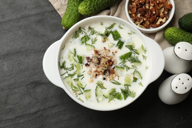 Photo of Fresh tasty cucumber soup and ingredients on black table, flat lay
