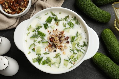 Photo of Fresh tasty cucumber soup and ingredients on black table, flat lay