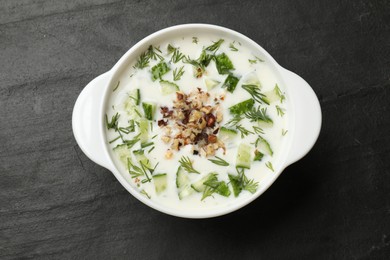 Photo of Fresh tasty cucumber soup on black table, top view