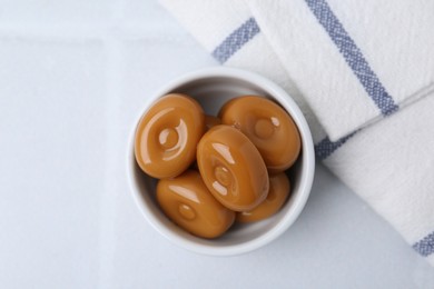 Photo of Tasty sweet caramel candies on white tiled table, top view