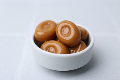 Photo of Tasty sweet caramel candies on white tiled table, closeup