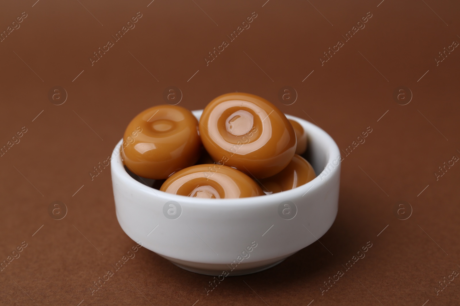Tasty sweet caramel candies on brown background, closeup Photo of Tasty sweet caramel candies on brown background, closeup