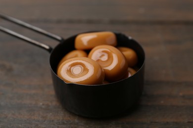 Photo of Tasty sweet caramel candies on wooden table, closeup
