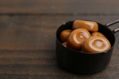 Photo of Tasty sweet caramel candies on wooden table, closeup