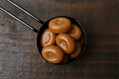 Photo of Tasty sweet caramel candies on wooden table, top view