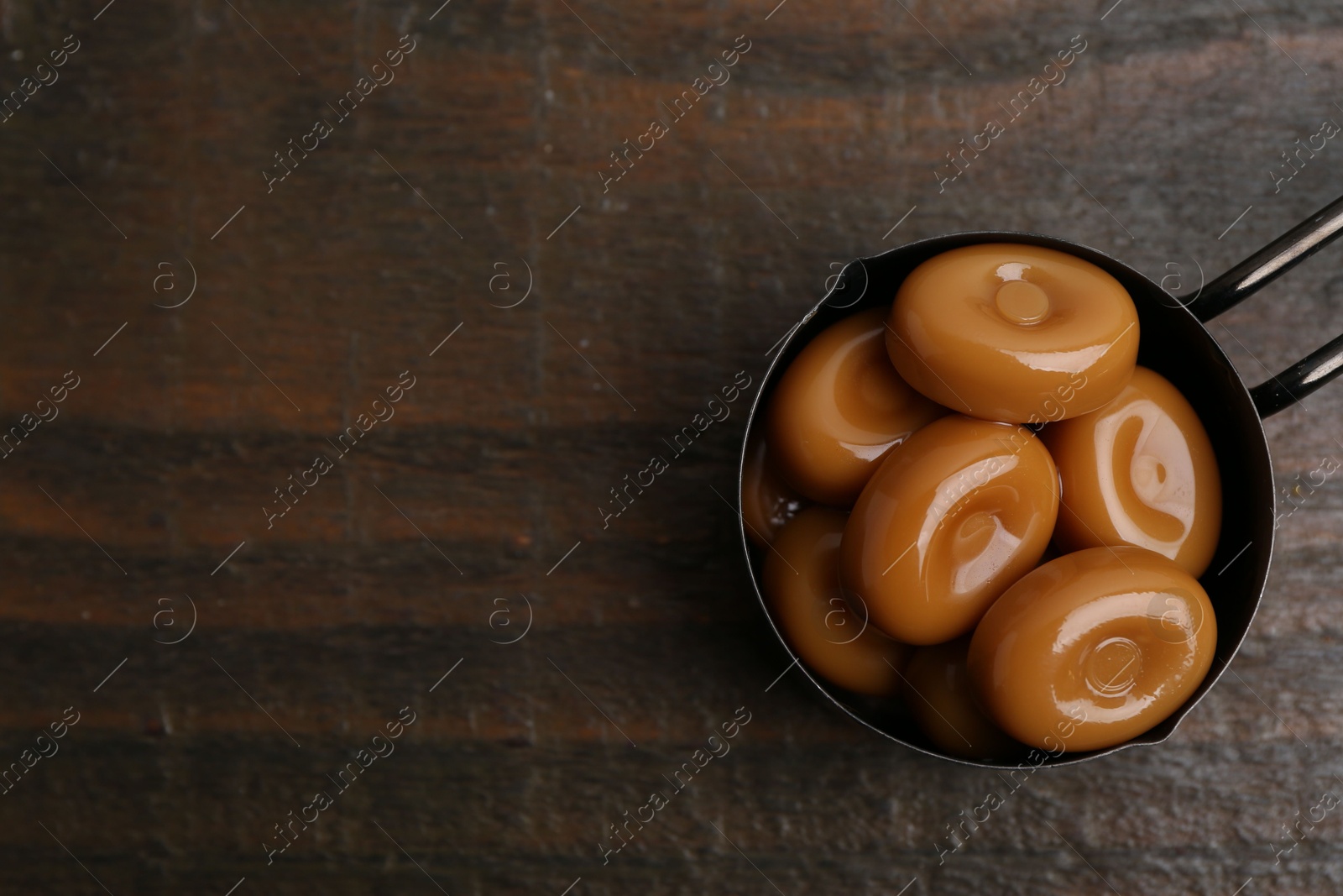 Tasty sweet caramel candies on wooden table, top view. Space for text Photo of Tasty sweet caramel candies on wooden table, top view. Space for text