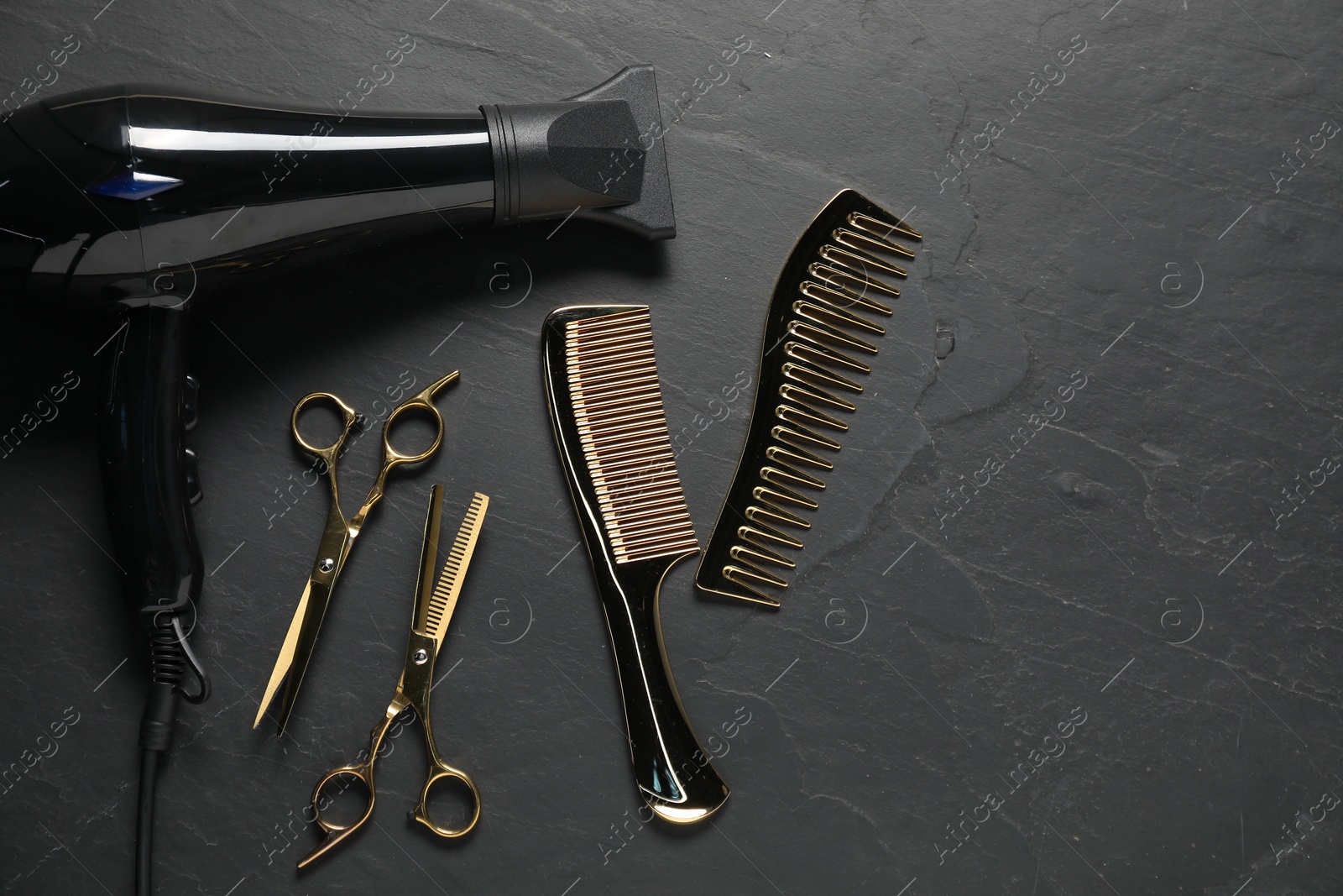 Photo of Different hairstyling tools on black textured background, flat lay. Space for text
