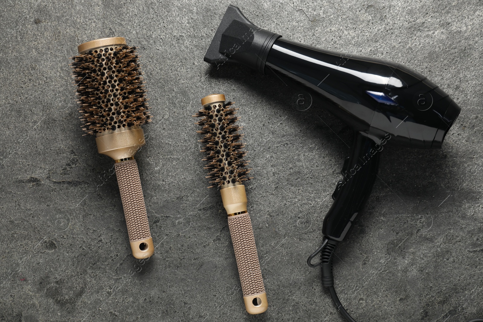 Hair dryer and brushes on grey textured background, flat lay Photo of Hair dryer and brushes on grey textured background, flat lay