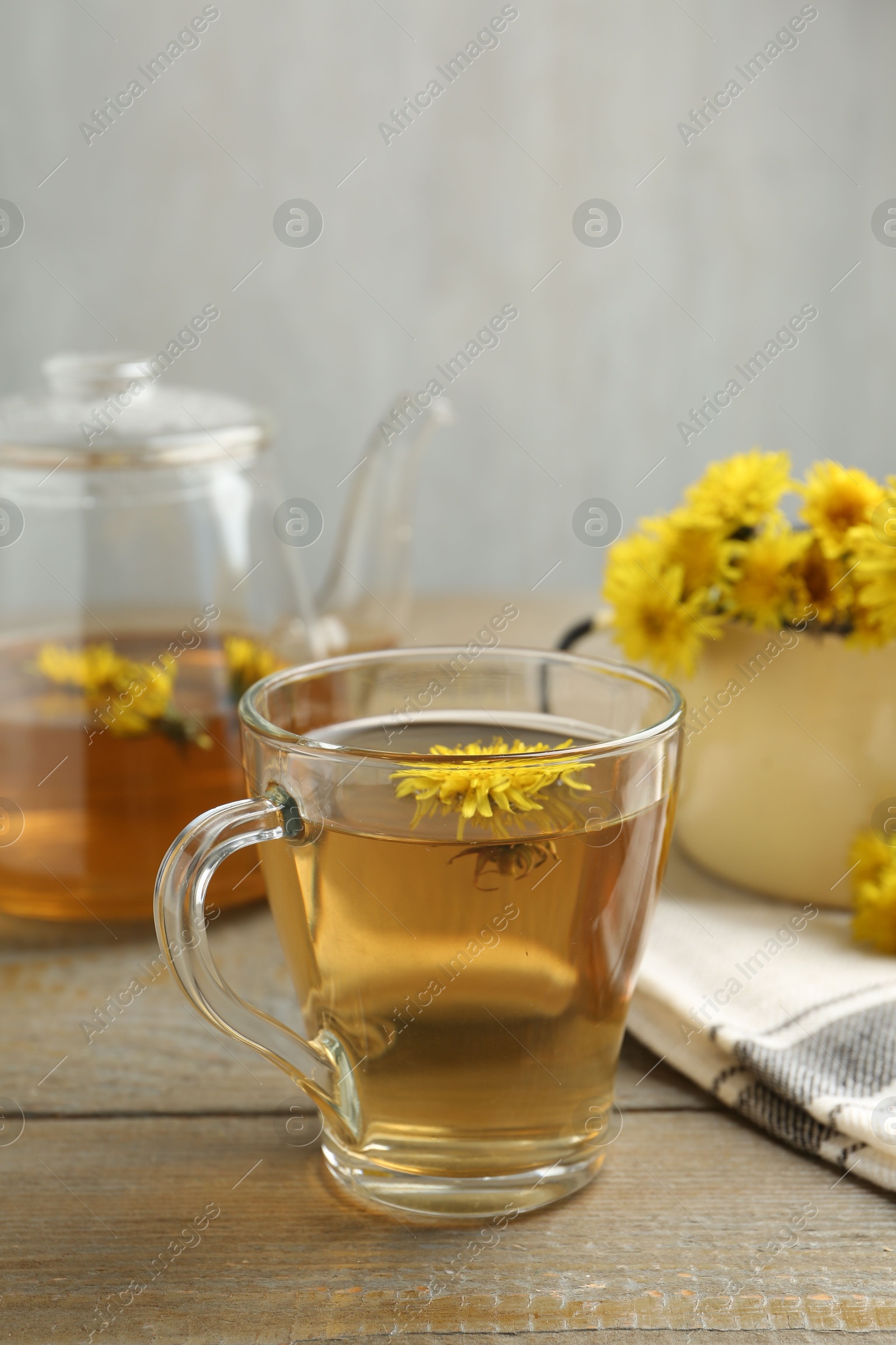 Refreshing dandelion tea and flowers on wooden table Photo of Refreshing dandelion tea and flowers on wooden table