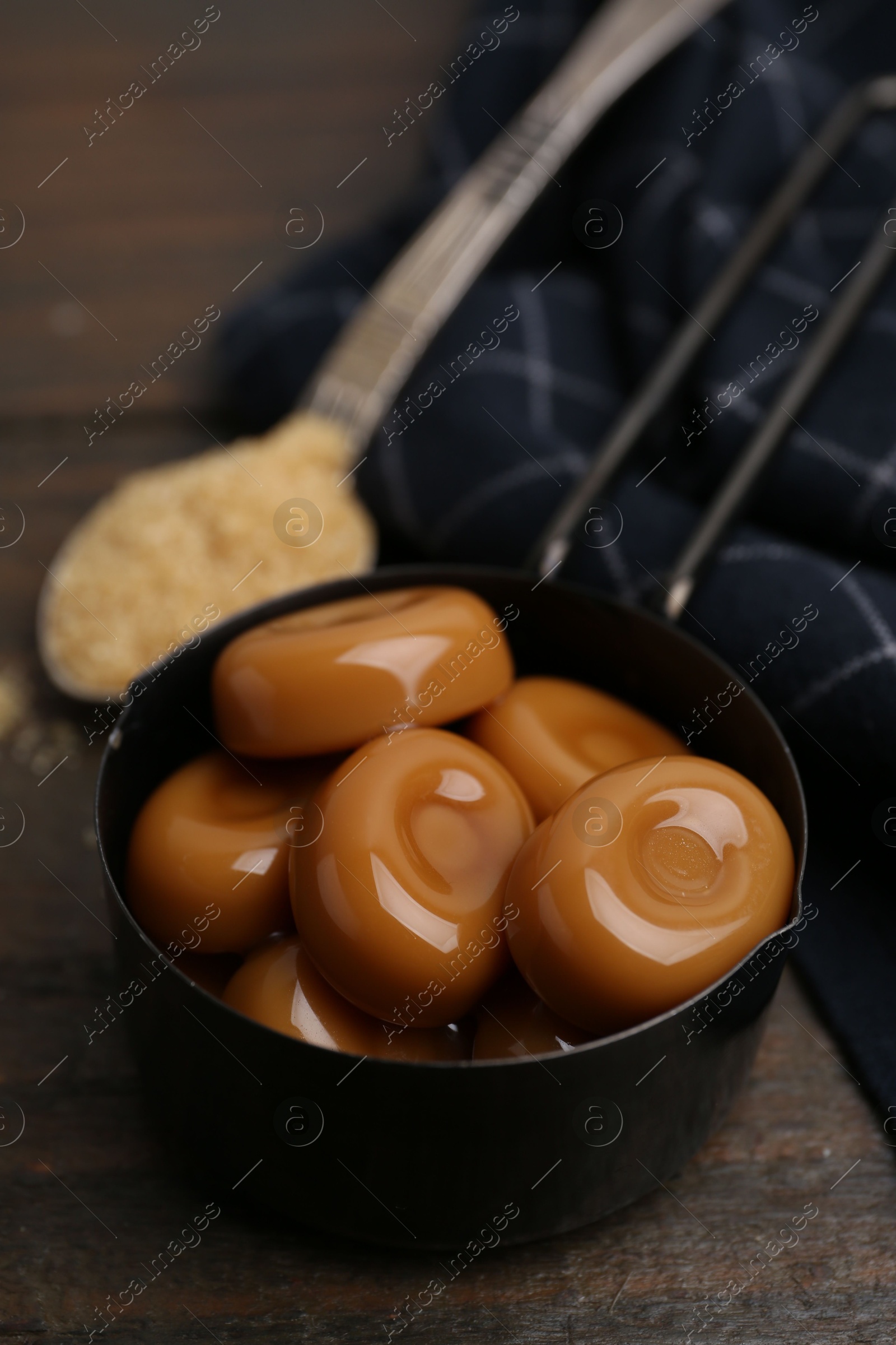 Tasty sweet caramel candies and sugar on wooden table, closeup Photo of Tasty sweet caramel candies and sugar on wooden table, closeup