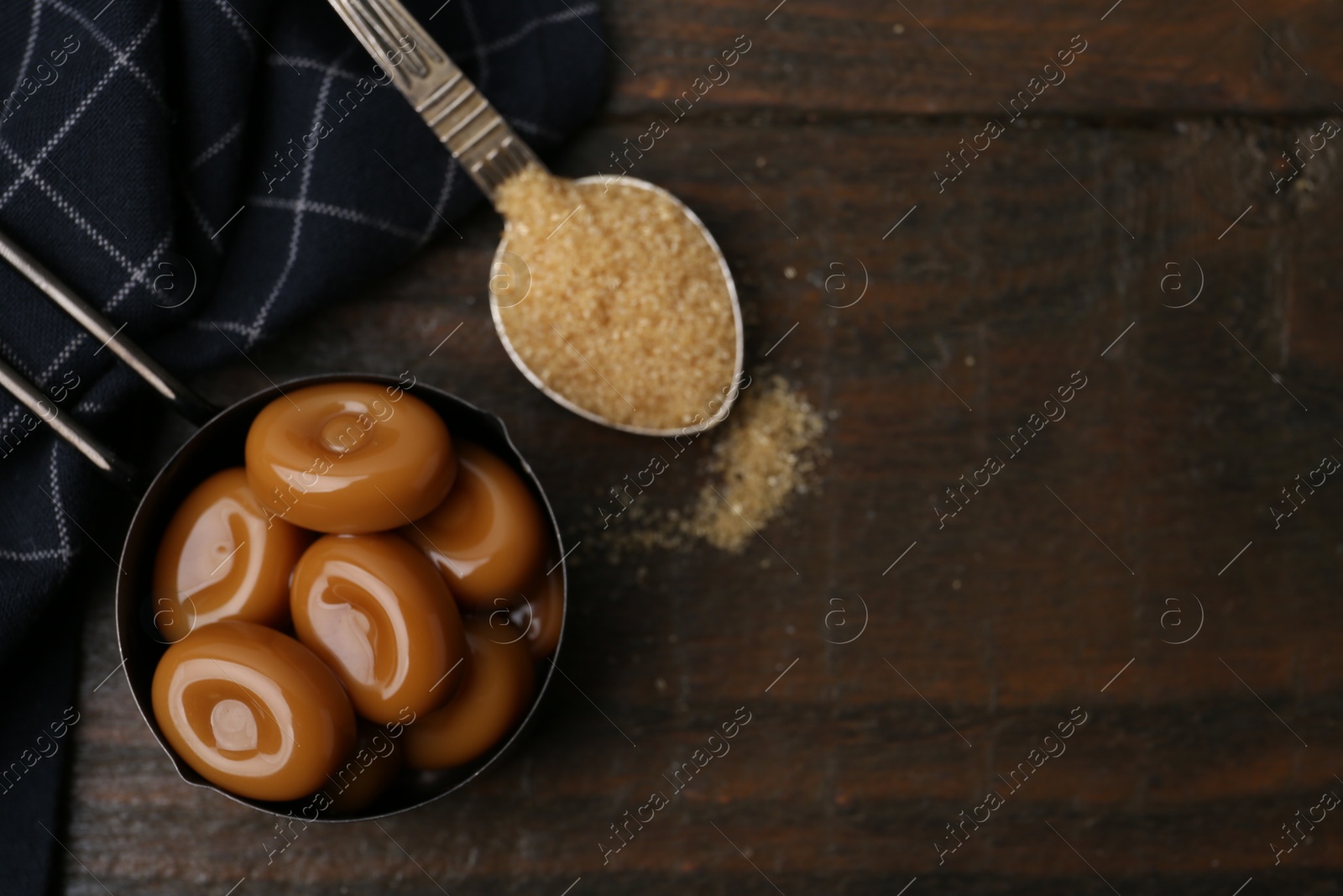 Tasty sweet caramel candies and sugar on wooden table, top view. Space for text Photo of Tasty sweet caramel candies and sugar on wooden table, top view. Space for text