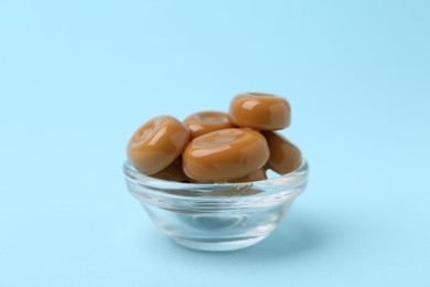Photo of Tasty sweet caramel candies on light blue background, closeup