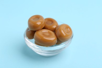 Photo of Tasty sweet caramel candies on light blue background, closeup