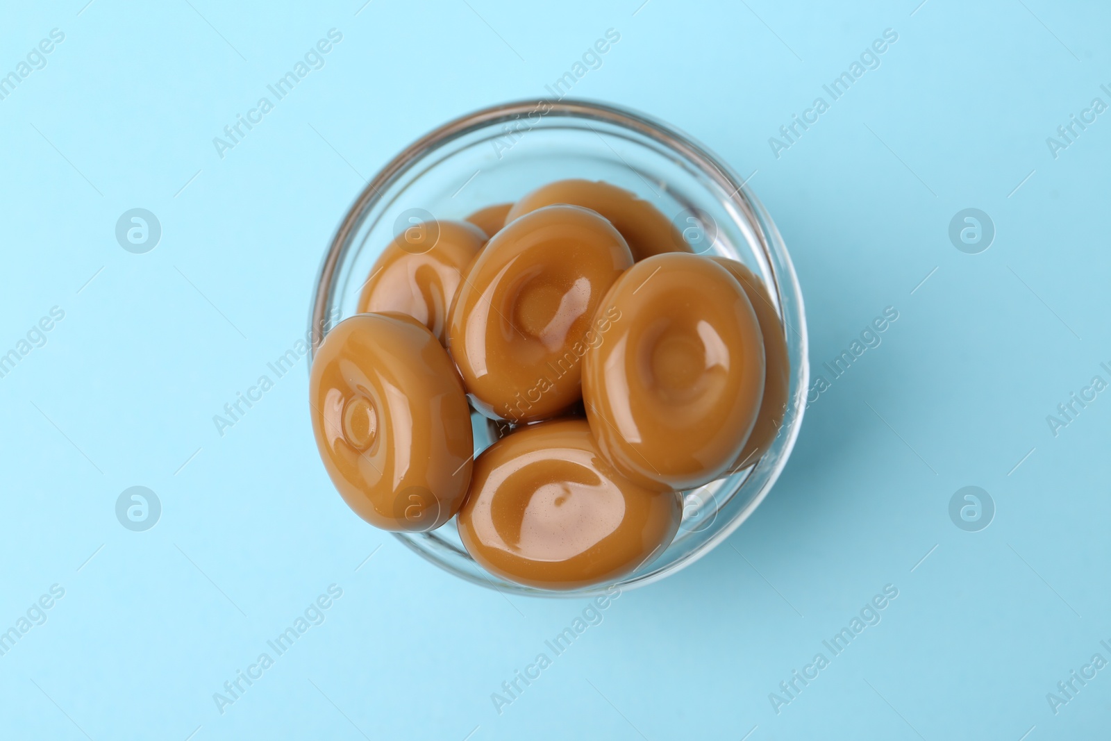 Tasty sweet caramel candies on light blue background, top view Photo of Tasty sweet caramel candies on light blue background, top view