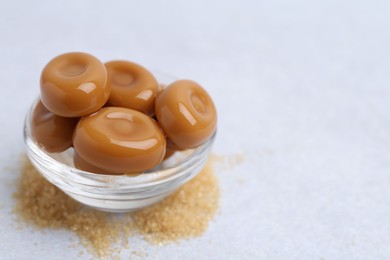 Photo of Tasty sweet caramel candies on white table, closeup. Space for text