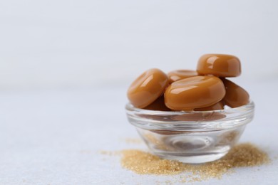Photo of Tasty sweet caramel candies on white table, closeup. Space for text