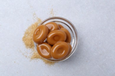 Photo of Tasty sweet caramel candies on white table, top view